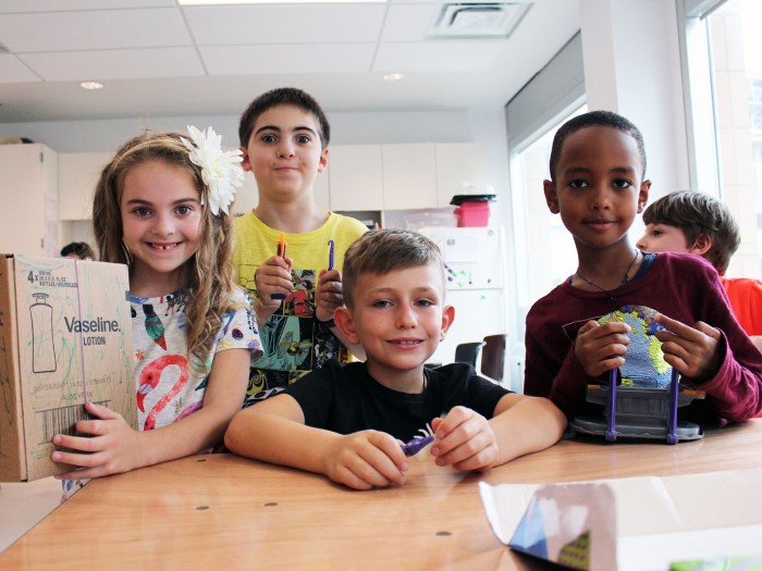 Four kids are sitting at the table and holding different staff in EarlyON Years Centre