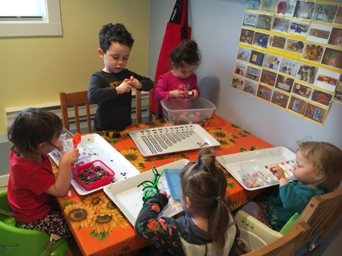 Five little kids are sitting at the table and playing in EarlyON Years Centre