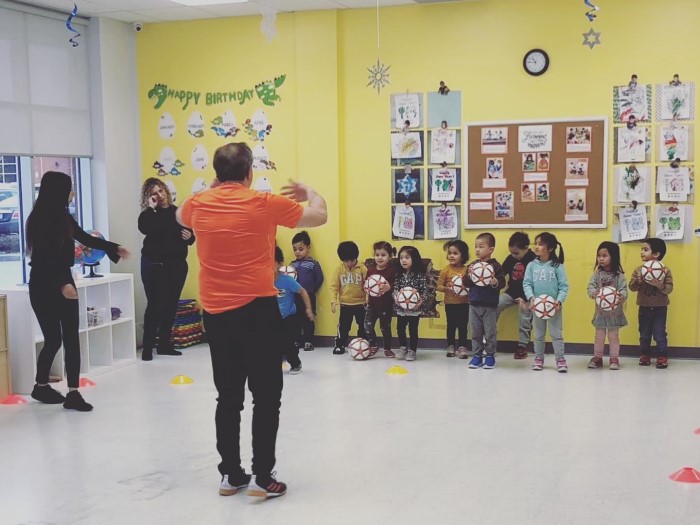 Kids are standing in line near the wall and listening to the teacher in EarlyON Years Centre