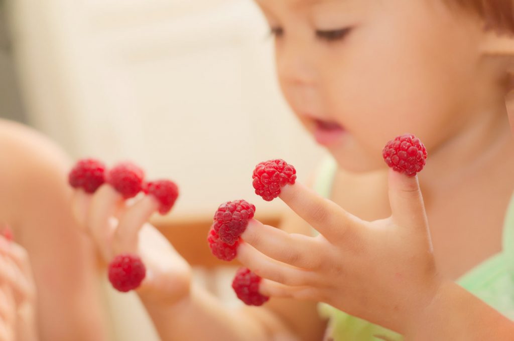 Baby girl eating raspberries