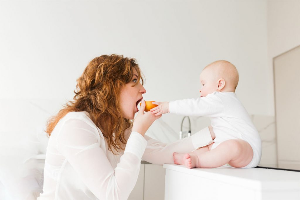 Woman eating orange with-little baby